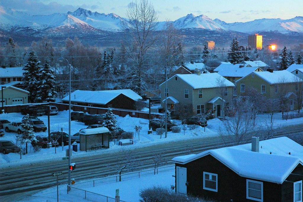 Lit windows in a snow-covered Anchorage neighbourhood at sunset